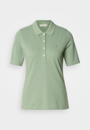 Polo verde hecho de algodón con corte ajustado, cuello tipo polo, mangas cortas y un pequeño logotipo bordado en el pecho.