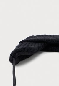 Sort ribbet tørklæde med en blød tekstur og en snor detalje. Stoffet fremstår som luksuriøst, og viser et enkelt, funktionelt design.