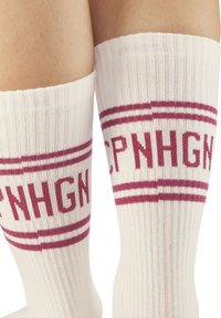 Calcetines blancos hasta la rodilla con textura acanalada, que presentan franjas de color marrón y el texto "CPNHGN" en negrita en la parte frontal.