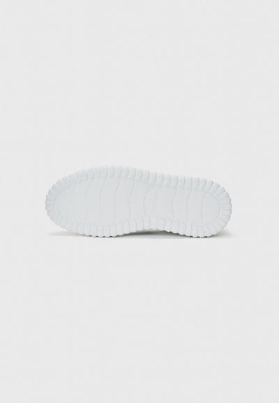White rubber sneaker outsole featuring textured grooves and a scalloped edge, designed for grip and durability.
