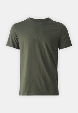 T-shirt in cotone verde oliva, collo a giro, maniche corte, con un sottile logo ricamato "GUESS" sul petto. Tessuto morbido, vestibilità standard.