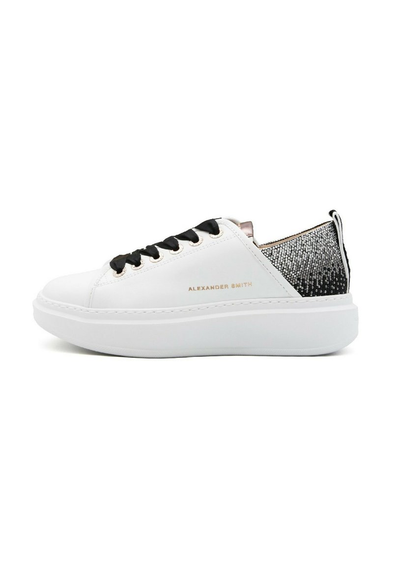 Sneaker bianca con materiale liscio, lacci neri, suola morbida e retro con un motivo testurizzato nero e argento. Logo del brand visibile sul lato.