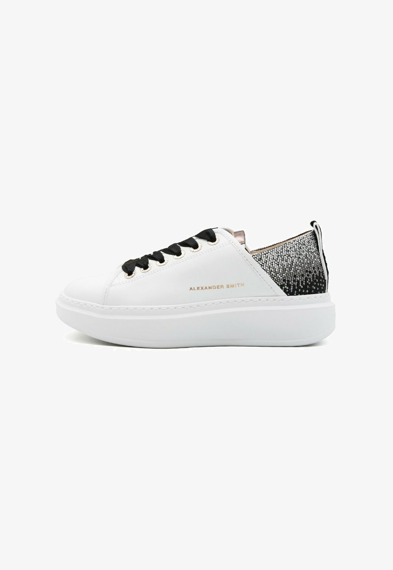 Sneaker bianca con materiale liscio, lacci neri, suola morbida e retro con un motivo testurizzato nero e argento. Logo del brand visibile sul lato.