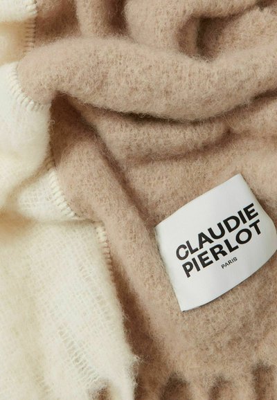 Écharpe beige et crème fabriquée en matériau doux et duveteux avec une texture subtile. Présente une étiquette en tissu avec "CLAUDIE PIERLOT PARIS" imprimée en noir.
