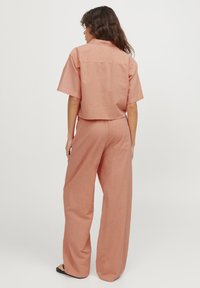 Kurzes, kurzärmliges Hemd und weit geschnittene Hose aus einem weichen Pfirsichstoff. Verfügt über eine Gesäßtasche und einen lässigen Schnitt. Geeignet für die Freizeit.