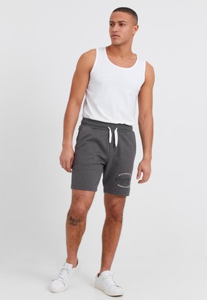 Shorts en coton gris avec cordon de serrage blanc, ornés d'un imprimé logo. Associés à un débardeur blanc sans manches et des baskets blanches.