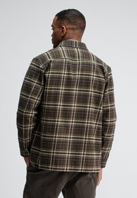 Groen en bruine geruite flanellen shirt met een licht getextureerde afwerking. Bevat een klassieke kraag en knoopmanchetten. Verborgen logo-label aan de zoom.