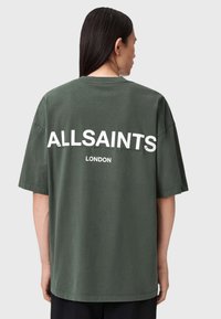 Tamsiai žalia didelio dydžio medvilnės marškinėliai, ant nugaros turintys didelį baltą užrašą "ALLSAINTS" ir "LONDON". Trumpi rankovės, laisvas siluetas.
