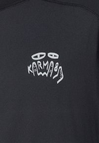 Black textile with a smooth texture featuring a graphic in white, displaying stylized eyes and the text "KARMA 8" in an artistic design.