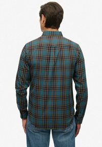 Camisa de cuadros para hombre en azul, verde y amarillo, con mangas largas, cuello abotonado y detalle de pliegue en la espalda.