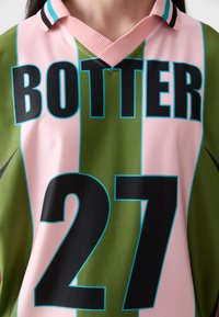 Green and pink sports jersey with black "BOTTER" text and "27" number. Features a v-neck collar with black and turquoise stripes. Smooth fabric.