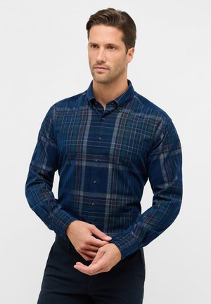 Camicia a quadri blu navy con bottoni, caratterizzata da una consistenza morbida, maniche lunghe e un colletto classico con diversi bottoni sul davanti.