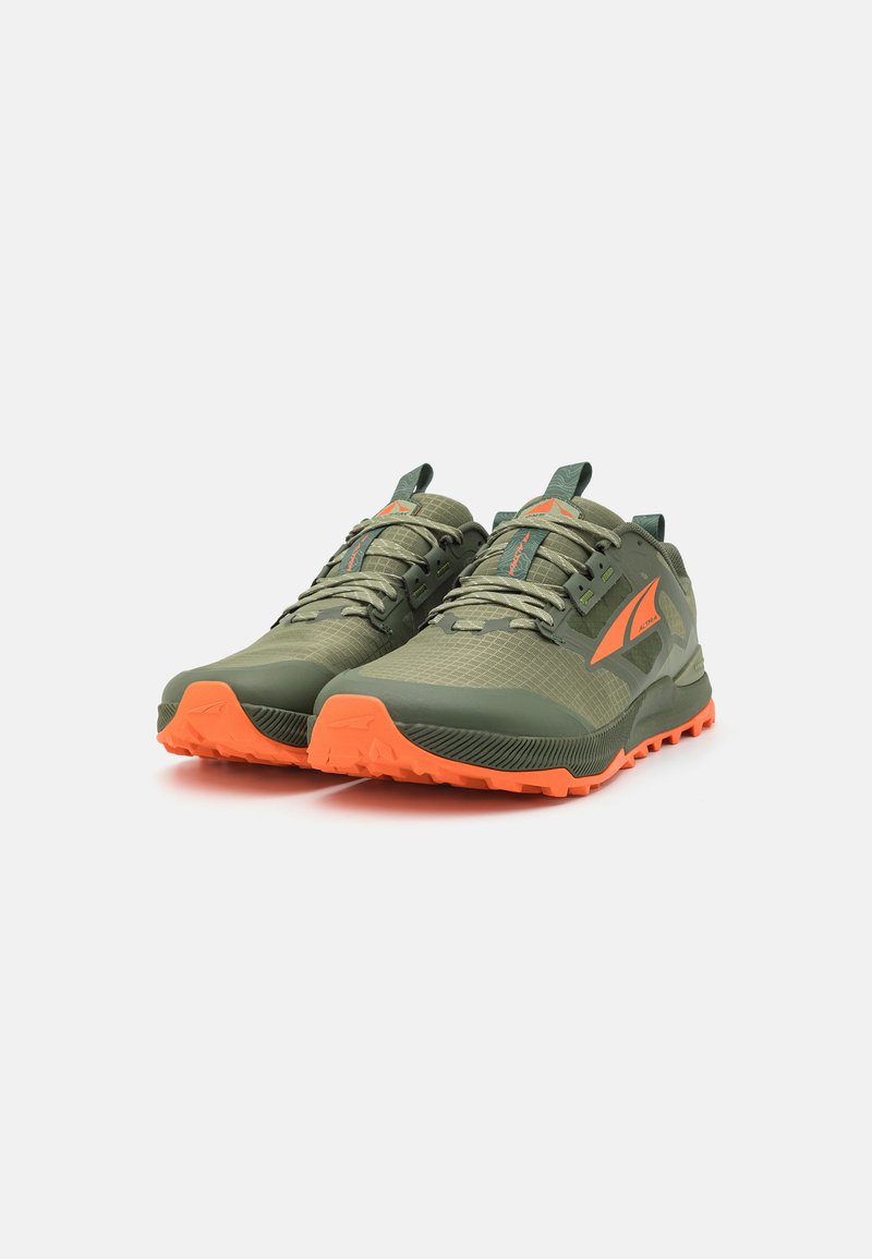 Zapatillas deportivas verdes con un acabado texturizado, con una suela y acentos naranjas, parte superior de malla transpirable y cordones reforzados.
