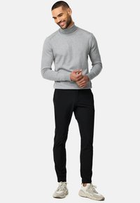 Grå turtleneck-tröja som matchas med svarta slim-fit byxor och ljusgrå träningsskor. Outfiten har en strömlindad, avslappnad design.