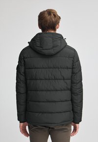 Svart pufferjacka med horisontella quiltade sektioner, huva och justerbara dragsko, tillverkad av vattenavvisande material.