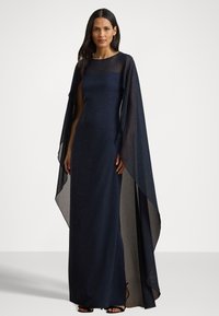 Marinblå kvällsklänning med figursydd upptill, lång genomskinlig kapuschongärmar, rak silhuett och golvlång fåll.