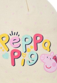 Kremowa dziana czapka z różowymi kropkami, z napisem "Świnka Peppa" w kolorowych literach oraz grafiką twarzy Świnki Peppy z kokardką.