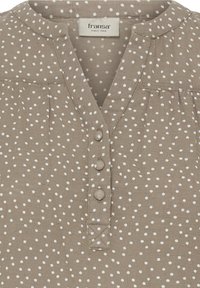 Blouse taupe à pois blancs irréguliers, col arrondi, trois boutons recouverts de tissu et étiquette de marque Fransa à l’intérieur du col.