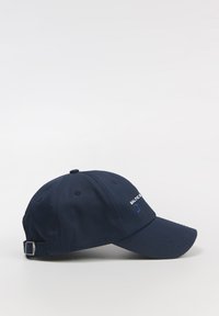 Granatowa czapka baseballowa wykonana z tkaniny, z zakrzywionym daszkiem, z haftowanym napisem na przodzie i regulowanym zapięciem z tyłu.