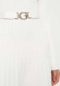 Cintura in tessuto bianco e testurizzato con una grande fibbia in argento lucidato a forma di 'G' e estremità regolabili, progettata per un look aderente.