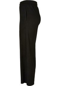 Pantalon noir côtelé avec une large ceinture élastique et une coupe droite. Comprend des poches latérales et un tissu doux et texturé.