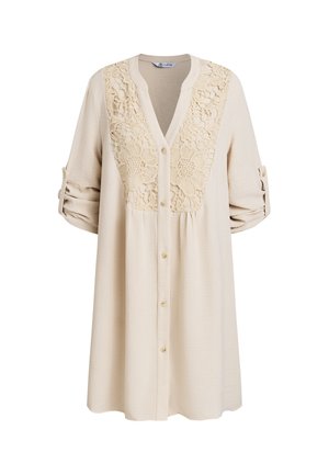 Beige jurk met lange mouwen, knoopsluiting, met een bloemige kanten inzet aan de voorkant en opgerolde mouwen die worden vastgezet met knoopsluitingen.