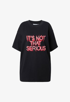 Schwarzes oversized T-Shirt mit kurzen Ärmeln. Mit einem Neon-grafik in Rot, auf dem steht: "ES IST NICHT SO ERNST". Aus glattem Baumwollstoff.