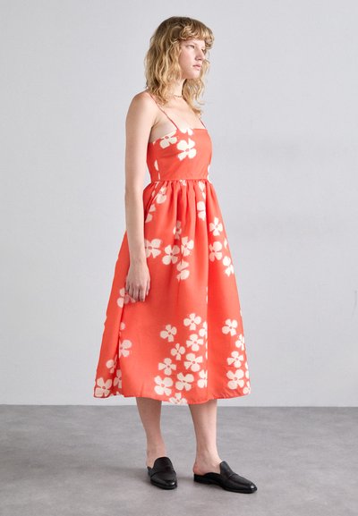 Rochie corai cu model floral alb, cu un corset ajustat și fustă evazată. Realizată dintr-un material fin, cu bretele subțiri și lungime până la jumătatea gambei.