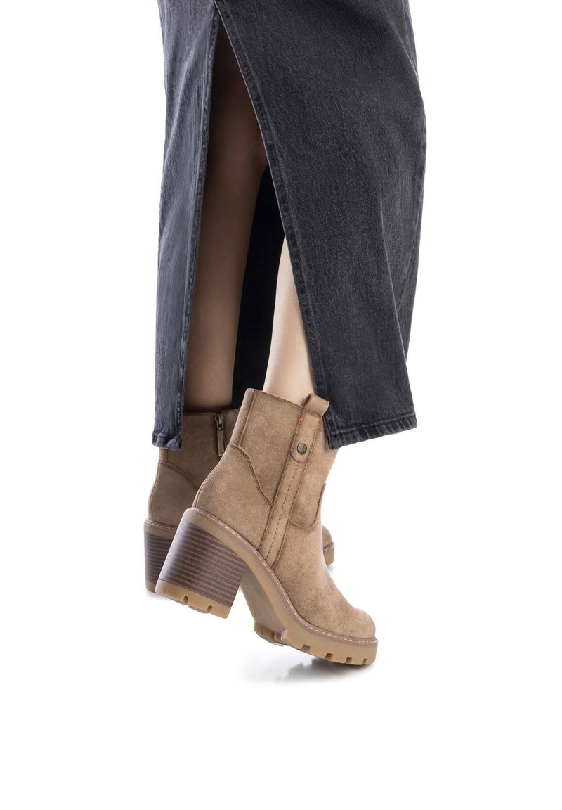 Stivali alla caviglia in camoscio color tan con tacco largo, dotati di una zip laterale e una suola testurizzata, abbinati a una gonna in denim nera con uno spacco.