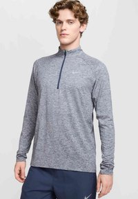 Langarm sporttop in gemêleerd grijs stof, met een half-zip ontwerp en een subtiele logo-accent. Ontspannen pasvorm met raglanmouwen.