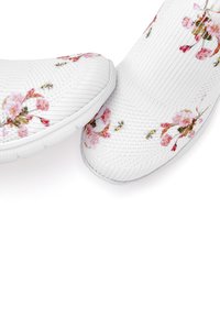 White slip-on shoes feature a textured knit upper adorned with pink floral patterns. The rubber sole has a rounded toe design.
