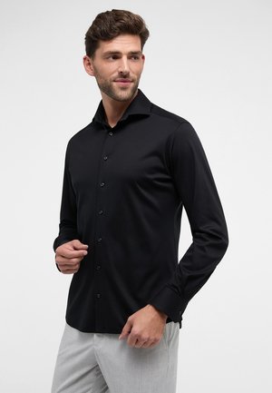 Schwarzes Langarmhemd aus glattem Stoff mit strukturiertem Kragen, vorderen Knöpfen und taillierter Passform. Minimalistischer Stil ohne Muster.