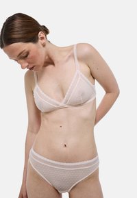 Ensemble de lingerie rose clair comportant un motif à pois, un ourlet en dentelle et des bretelles ajustables. Le soutien-gorge est conçu avec des bonnets souples et est accompagné d'une culotte assortie.