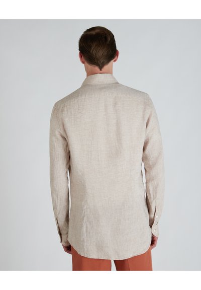 Camisa de manga larga color beige claro, hecha de lino. Presenta un cuello abotonado, dobladillo recto y un patrón texturizado y tejido.
