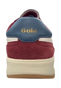 Baskets en suède rouge avec un onglet de talon en cuir bleu, des accents blancs et une semelle en caoutchouc beige. Présente le logo doré "Gola" sur le talon.