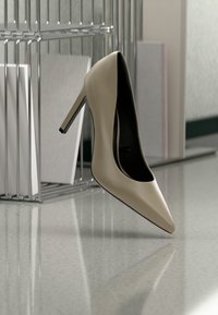 Escarpin beige à talon haut reposant sur un sol réfléchissant à côté d'un organiseur de fichiers en métal contenant des documents, dans un cadre de bureau.