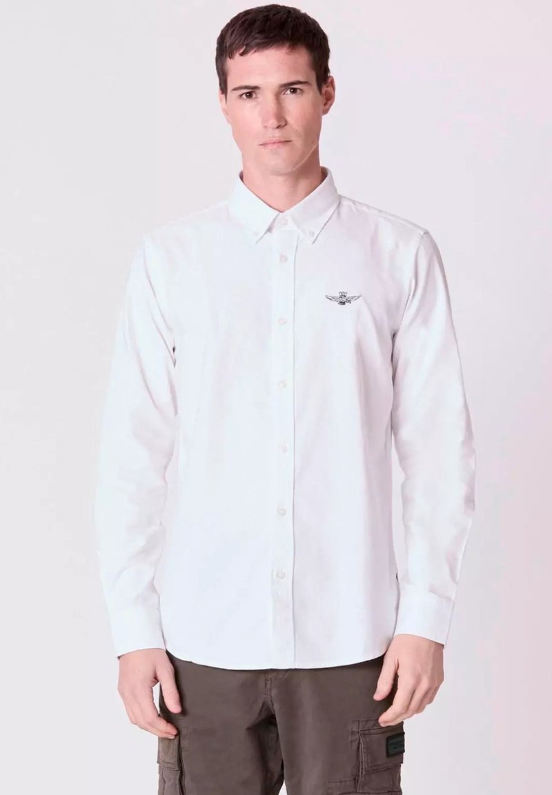 Camicia bianca a maniche lunghe con bottoni, realizzata in cotone, caratterizzata da un piccolo logo sul lato sinistro del petto e da un design di colletto classico.