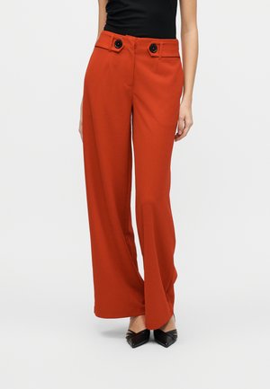 Pantalon rouge à jambes larges en tissu lisse, avec deux boutons noirs à la taille et des poches avant ajustées pour plus de détails.