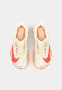 Sportschoenen met een ademend mesh bovenwerk in crème, voorzien van neon groene en koraalkleurige accenten. Dikke zool met een gestructureerd patroon, reflecterende details en veters.