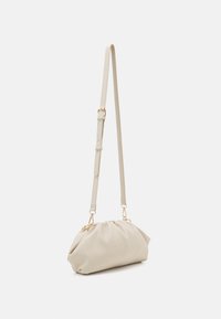 Beige kabelka s nařaseným designem, hladkým povrchem, nastavitelným popruhem a zlatými kovovými akcenty, prezentována z bočního pohledu.