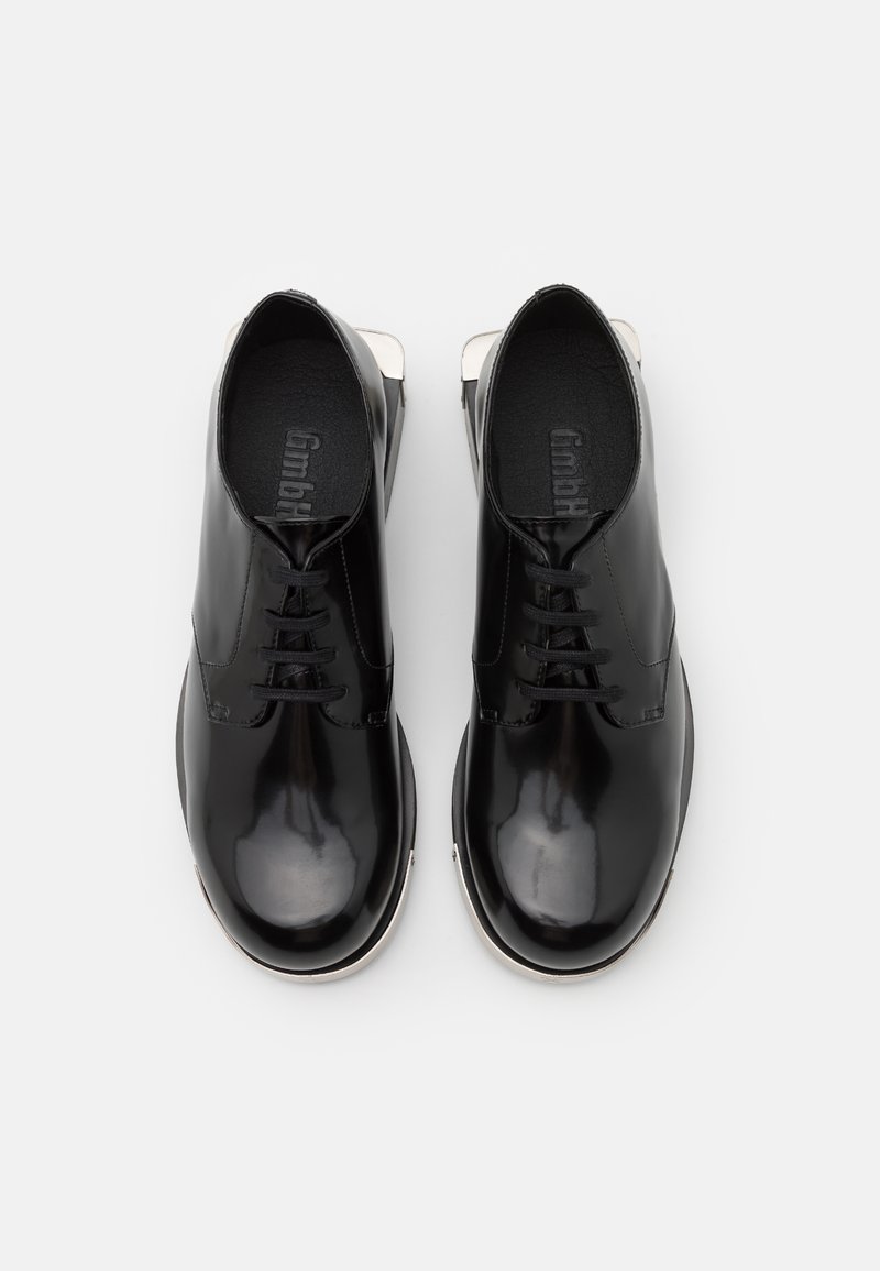 Scarpe nere in vernice con lacci piatti, punta arrotondata e finitura liscia. Presentano un design elegante con dettagli in argento sul tallone.