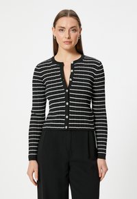 Svartvit randig cardigan med ribbad textur, rund halsringning och fem metallknappar fram. Kort modell.