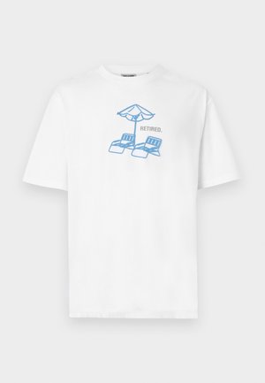 Vit T-shirt med blå illustration av två solstolar under ett strandparasoll och ordet "RETIRED." tryckt bredvid dem.