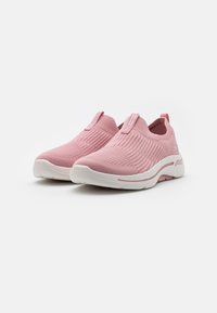 Zapatillas de punto rosas tipo slip-on con parte superior texturizada, suela de goma blanca y sutil acento rosa. Presentan una lengüeta para facilitar su uso.