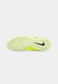 Potplat Nike trkačkog shaqa u neonsko žutoj boji s teksturiranim uzorkom za grip i crnim swoosh logom na svijetlosivoj pozadini.