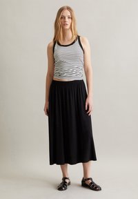 Stribet sort og hvid tanktop parret med en sort maxiskørt. Outfittet har en afslappet pasform og let materiale.