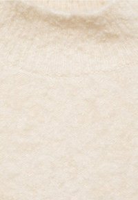 Neulepusero kreemivärvi, pehmea tekstuuri ja soonikkoorso. Kehapool on diskreetne diagonaalpattern, mis lisab sügavust.