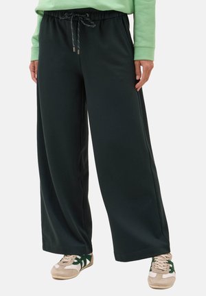 Pantaloni della tuta larghi di colore verde scuro con vita elasticizzata e cordoncino. Realizzati in tessuto morbido, presentano tasche laterali e gambe larghe.