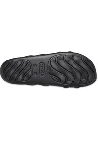 Black rubber shoe sole with textured surface and wave pattern for grip. Features ventilation holes and size indication (W 7) on the base.