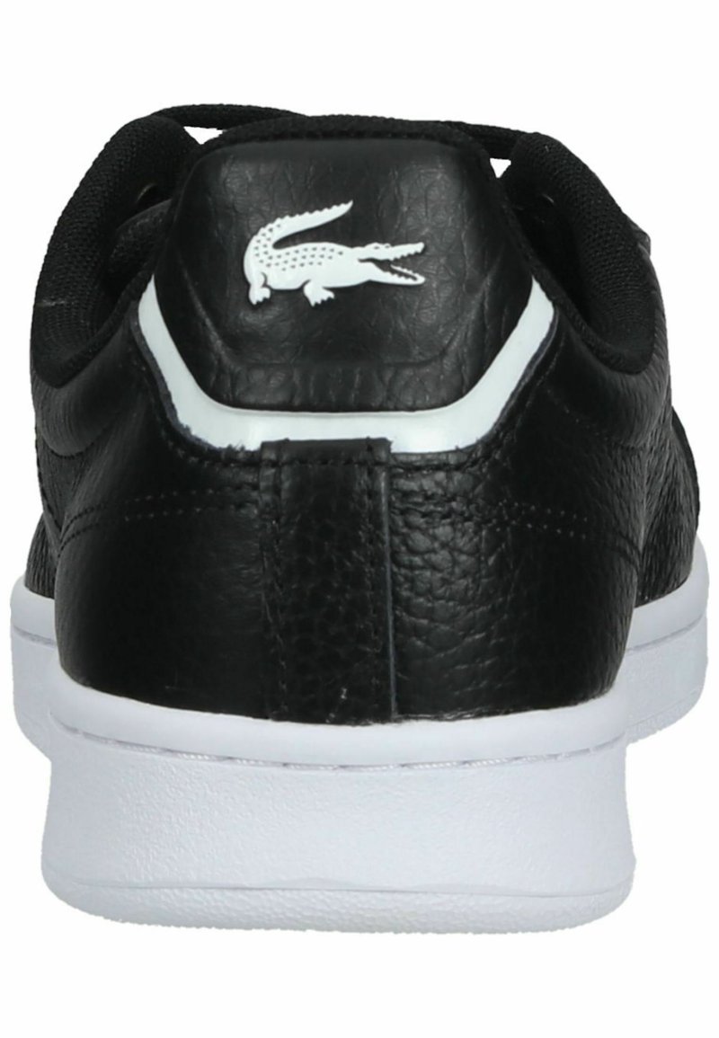 Baskets en cuir noir avec semelle blanche, présentant un logo crocodile blanc sur le talon et un col rembourré noir.